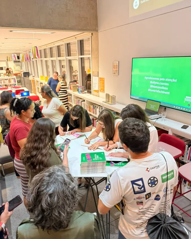 Mesa de autógrafos vista de cima, com pessoas em volta esperando para ter o livro assinado.